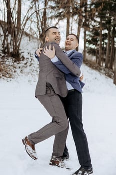 Two men in suits are hugging each other in the snow. Scene is joyful and happy photo