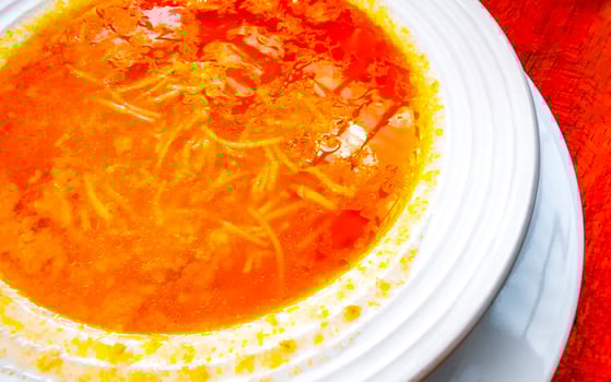 Noodle pasta soup a piece on white plate greens Mexico. photo