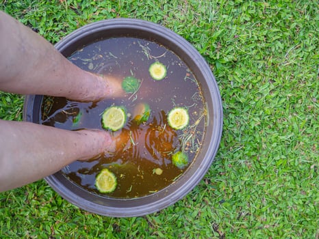 Close-up of the foot spa with herbs water for relaxation treatment. A senior woman who has ankle pain uses herbal treatment to relax the muscles by soaking warm water that is boiled from herbs photo