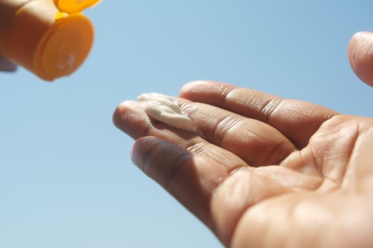 Close up of person hand using sunscreen cream outdoor photo