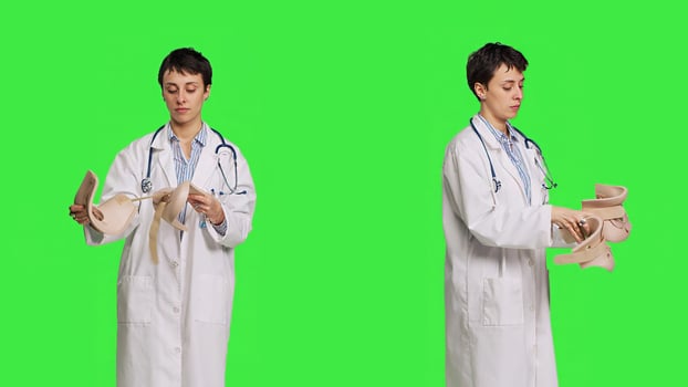 Orthopedics specialist holding a cervical neck collar against greenscreen backdrop, medical foam tool helping with fractures and physical therapy. Medic uses brace for accident trauma. Camera B. photo