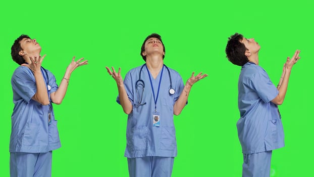 Hospital nurse worshipping God by prayer against greenscreen backdrop, praying to jesus christ and having hope in christianity and spirituality. Medical assistant doing meditation. Camera B. photo