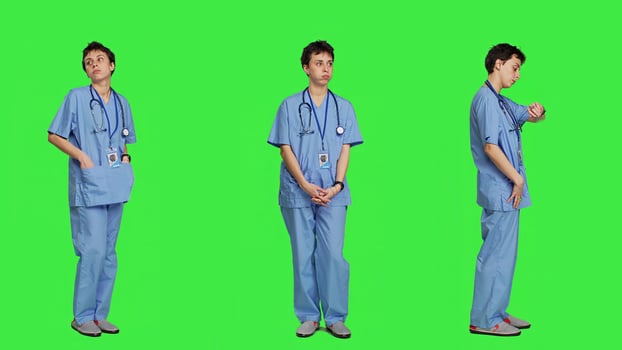 Stressed nurse checking time on watch and waiting for patient to arrive at checkup examination, being impatient against greenscreen backdrop. Medical assistant with scrubs and stethoscope. Camera A. photo