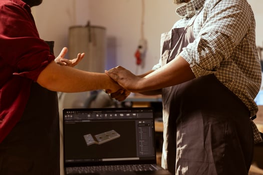 Carpenter meeting with client in studio, shaking hands and talking about commissioned furniture assembling job. Man greeting customer, showing him blueprint on CAD software on laptop photo