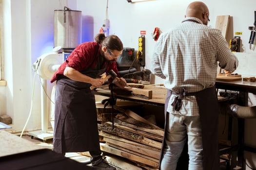 Manufacturer carving designs into wood using chisel and hammer, wearing safety glasses to avoid injury. Artisan shaping wooden pieces using protective equipment to prevent workplace accidents photo