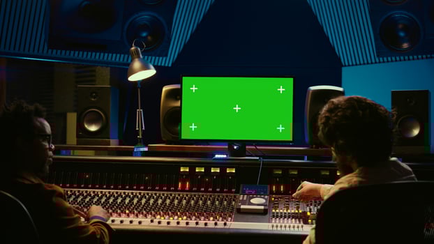 Team of music engineer and artist recording tracks on greenscreen, processing sounds to create a new song. Musician working closely with producer to make high quality tunes. Camera A. photo