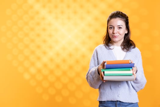 Portrait of happy woman holding pile of books, enjoying reading hobby for relaxation purposes. Upbeat bookaholic person with stack of novels in arms enjoying leisure time, studio background photo