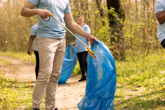 Male volunteer collecting rubbish to fix pollution issues within the habitat, protecting the natural ecosystem. Activist doing voluntary work to clean the woods from trash and plastic waste. photo