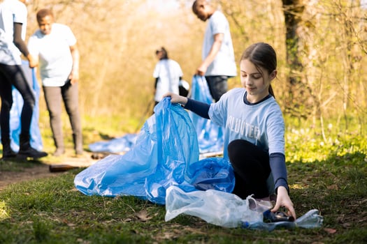 Young girl activist collecting trash and recycling in disposal bags, clearing the natural forest environment and combating illegal dumping. Ecologic volunteer grabbing plastic waste and junk. photo