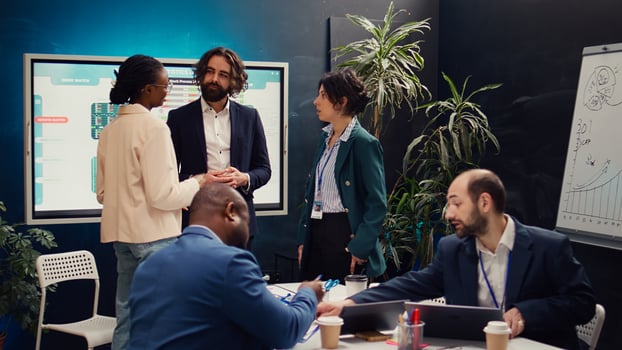 Team of startup colleagues preparing their presentation speech in front of the interactive board. Office employees meeting in a boardroom to review performance metrics as a group. Camera B. photo