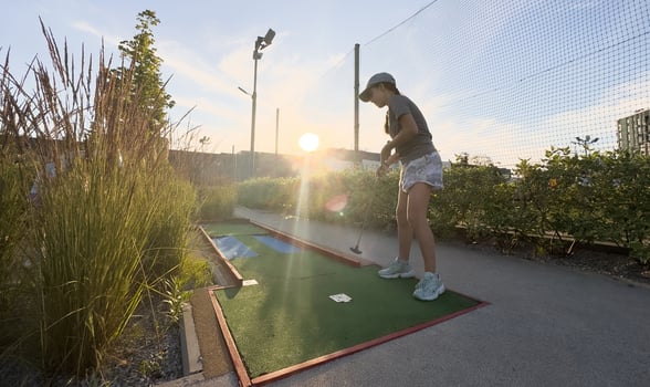 Mini Golf - girl playing Golf on green grass at sunset photo