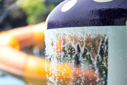Mushroom shaped fountain release a stream of water. that overflows like rain on sunny days at the water park. The background image was blurred with a big red black slider. photo
