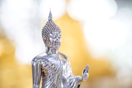 Silver shining Buddha statue with gold and silver background. photo