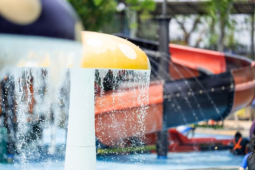 Mushroom shaped fountain release a stream of water. that overflows like rain on sunny days at the water park. The background image was blurred with a big red black slider. photo
