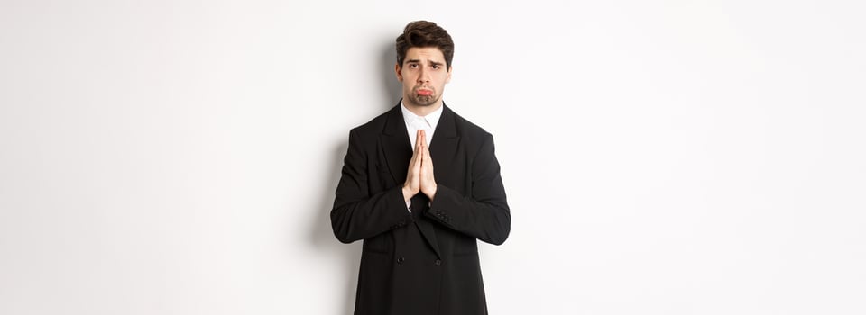 Miserable clingy guy need help, pouting silly and begging for something, asking for favour, standing against white background in black suit photo