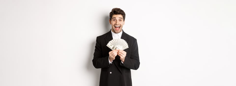 Portrait of handsome successful businessman in trendy suit, showing money and smiling amazed, earn cash, standing over white background photo