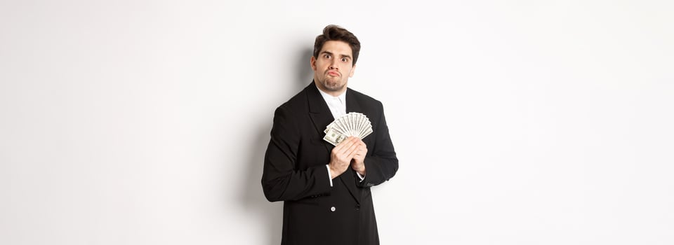 Image of greedy guy in black suit, holding money and unwilling to share, standing over white background photo