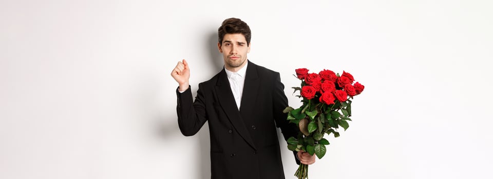 Image of elegant and sassy man in black suit, looking confident and holding bouquet of red roses, going on a romantic date, standing against white background photo