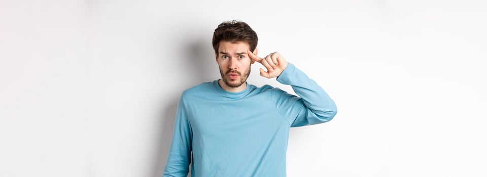 Annoyed caucasian man roll finger on temple, are you stupid or crazy gesture, scolding someone acting strange, standing in sweatshirt over white background photo