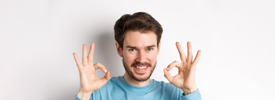 Close-up of confident young man smiling, showing okay signs, praising excellent choice, approve something good, standing over white background photo