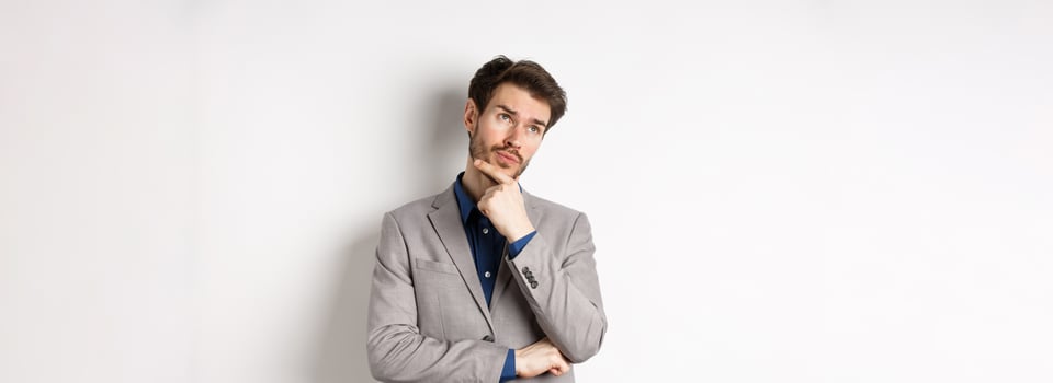 Thoughtful businessman in grey suit look at upper left corner logo, thinking or making choice, pondering plan, standing against white background photo