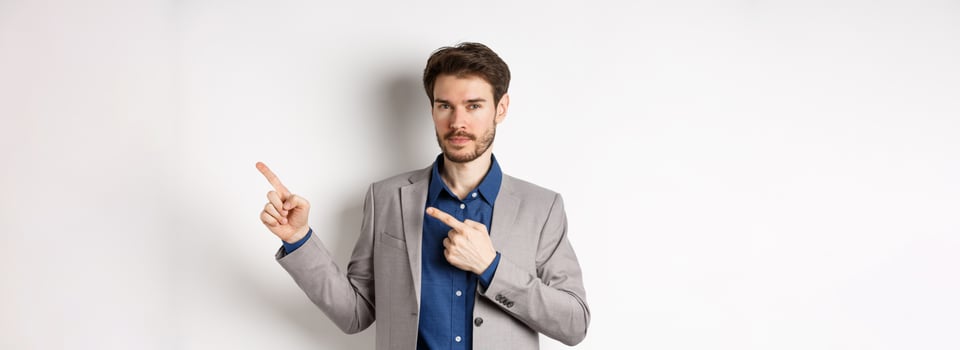 Confident handsome man in business suit pointing at upper right corner logo, showing company banner and smiling assertive, standing on white background photo