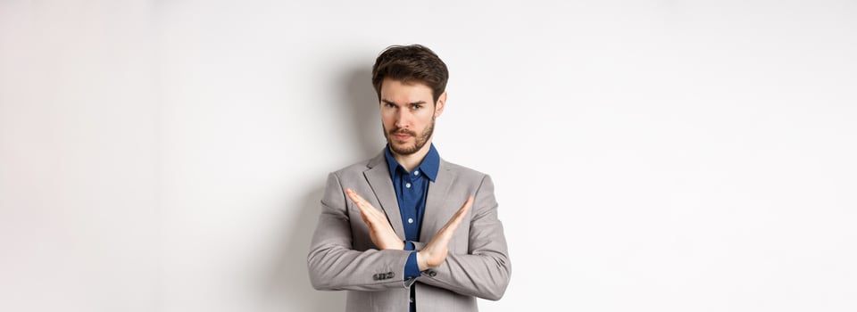 Serious business man making cross and says no, looking determined, disagree and prohibit something bad, tell to stop, standing in suit on white background photo