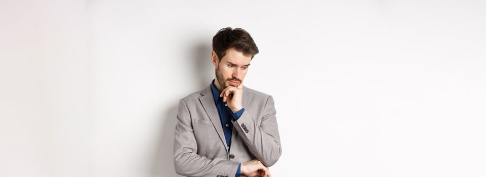 Thoughtful businessman in suit looking down and thinking, making decision, standing on white background photo
