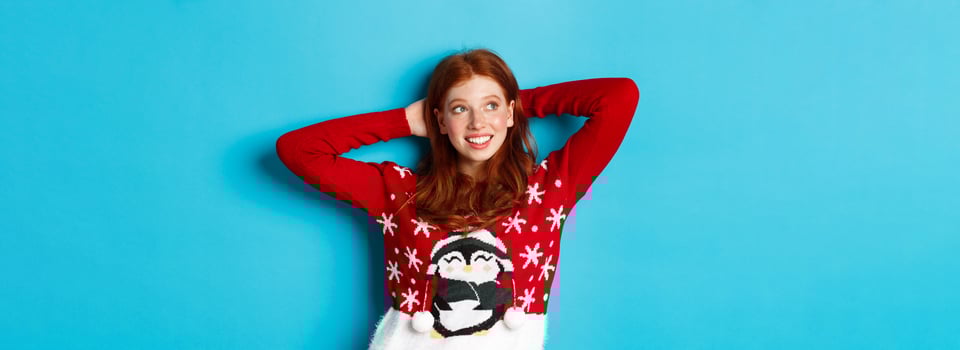 Winter holidays and celebration concept. Relaxed teenage girl holding hands behind head and looking left at promo, resting on Christmas Eve, standing over blue background photo