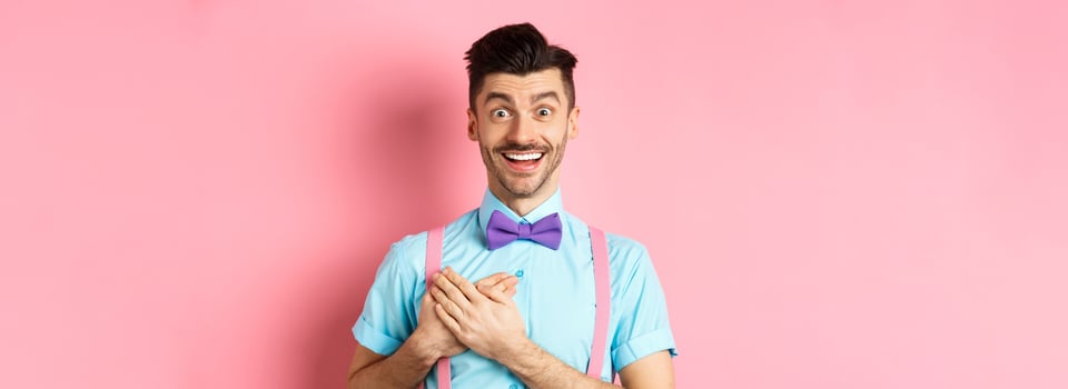 Valentines day and romance concept. Happy man in love holding hands on heart and looking with sympathy at lover, standing on romantic pink background photo