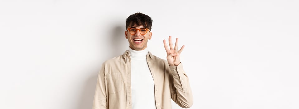 Handsome young man making order, showing number four fingers and smiling, standing on white background photo