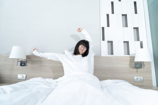 Little Asian young Glasses Girl stretches oneself on the bed in the morning with refreshing and happiness. photo