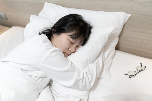 Asian cute young woman in white long arm pajamas lie on her side on the bed photo