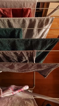 Towels and clothes are neatly hung to dry indoors on a rack photo