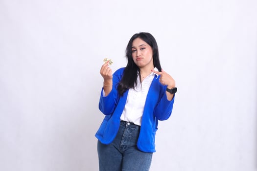beautiful adult office woman wearing blue formal suit standing pouting to camera holding bitcoin while pointing at it isolated white background. for transaction, investment, business content photo