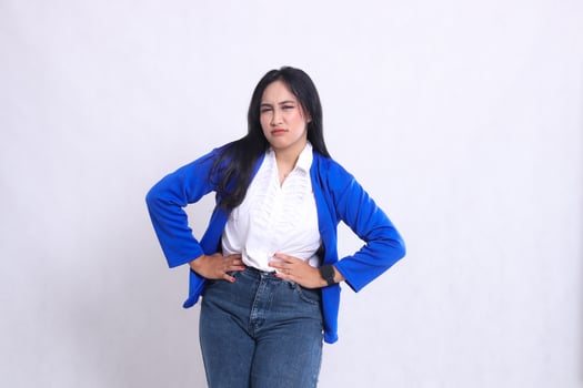 expression of beautiful young office woman wearing blue formal suit standing sad both hands holding her stomach which hurts. for company content, health, business, care, photo