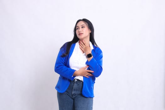gesture of beautiful young office girl wearing blue formal suit standing candid weak thirsty hand holding throat. for company content, health, business, care, drinks photo