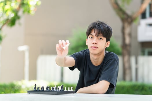 Asian teenage boy playing chess board, Asian boy relaxing hobbies playing a game of chess outdoor photo