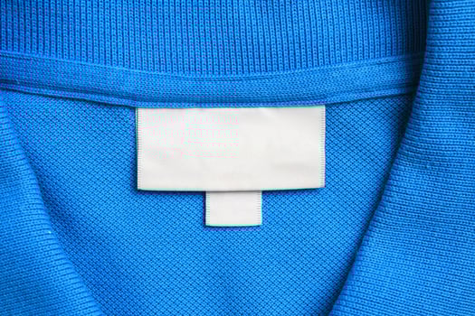Blank white laundry care clothes label on blue shirt fabric texture background photo