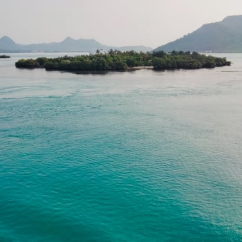 the view of an island in the middle of the ocean with a beautiful sky decorated photo