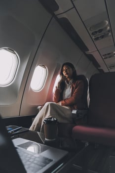 Photo of a frustrated woman sitting on an airplane with her head in her hands. Asian woman sitting in a seat in airplane