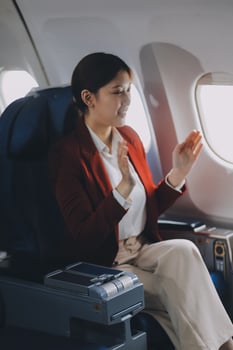 A young Asian woman, seated as an airplane passenger, contemplates dollar bills, reflecting on lucrative opportunities and aspirations towards billionaire status. photo