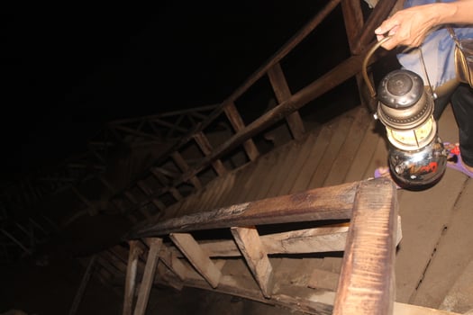 Thai Woman is holding a kerosene lamp in her hands while walking down the massive wodden stairs in the Cave in Thailand photo