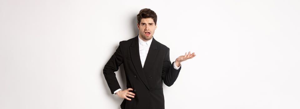 Portrait of arrogant man in black suit, looking confused and disappointed, complaining about something strange, standing over white background photo