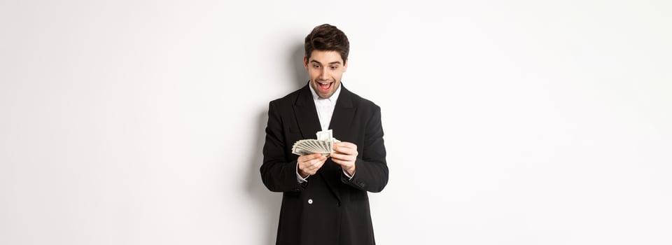 Image of excited handsome businessman, counting money and smiling amused, standing against white background in suit photo