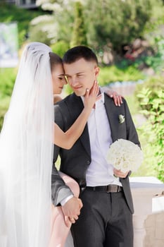 A man and a woman are hugging each other, with the man holding a bouquet of white flowers. The scene is likely a wedding or a special occasion, as the couple is dressed in formal attire photo