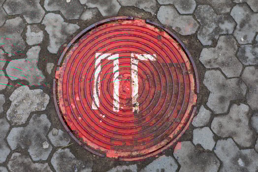 Red sewer manhole surrounded by decorative stone masonry. photo