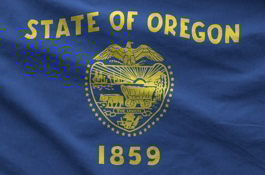 Oregon US state flag depicted on folded wavy fabric of old cloth photo