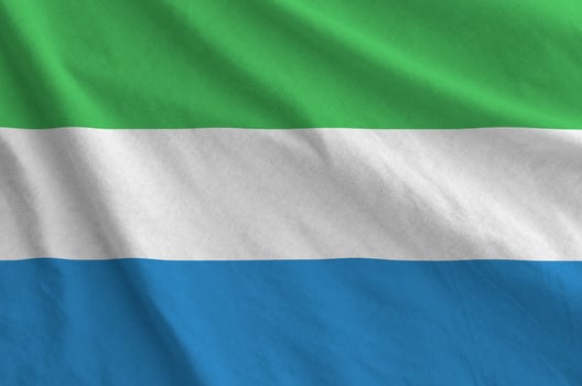 Sierra Leone flag depicted on folded wavy fabric of old cloth photo