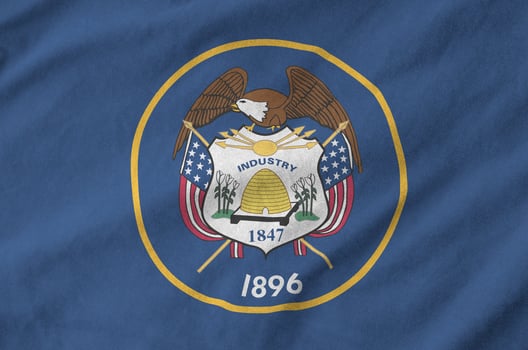 Utah US state flag depicted on folded wavy fabric of old cloth photo